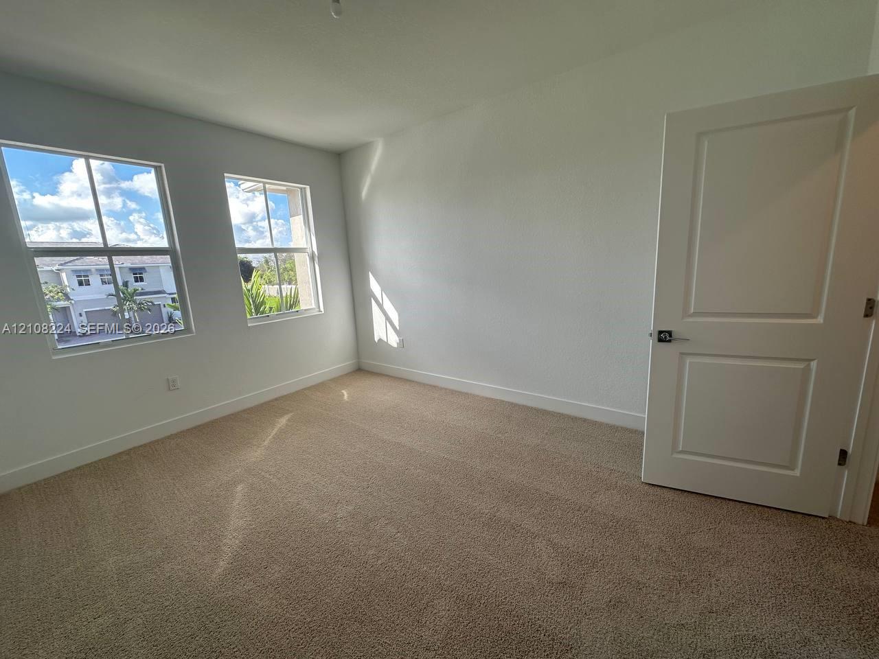 Neutral-toned carpeting, two dual-pane windows, and a classic two-panel interior door