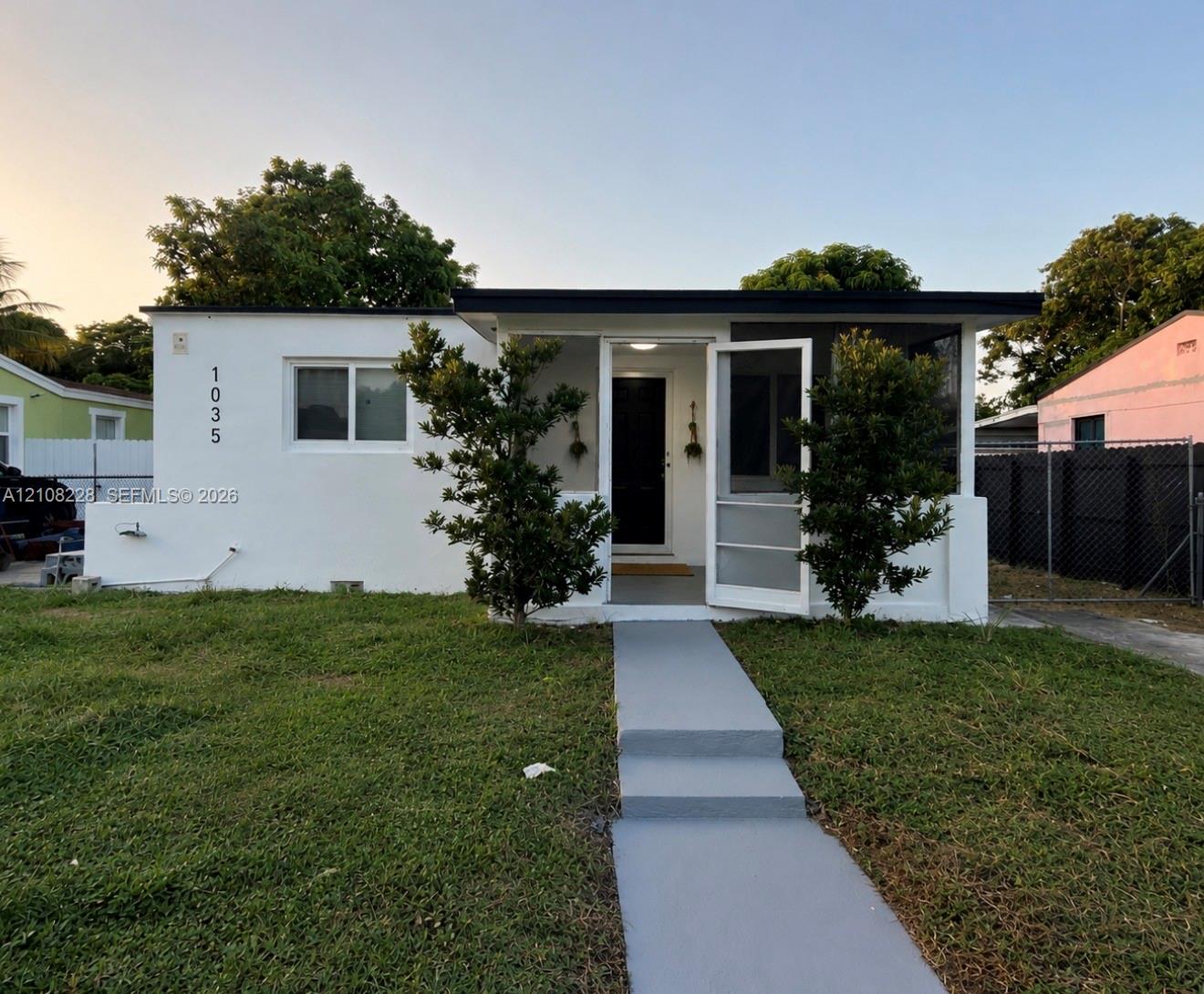 Stucco exterior with a flat roofline, covered front entryway, screen door, and paved pedestrian walkway Stucco exterior with a flat roofline, covered front entryway, screen door, and paved pedestrian walkway