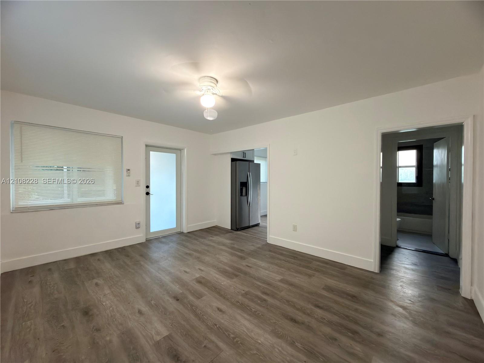 Interior space featuring wood-finish flooring, a neutral color palette, a ceiling-mounted light fixture, and an exterior door with glass paneling