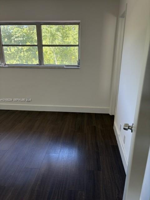 Room interior featuring dark wood-finish flooring, neutral wall tones, and a multi-pane horizontal window