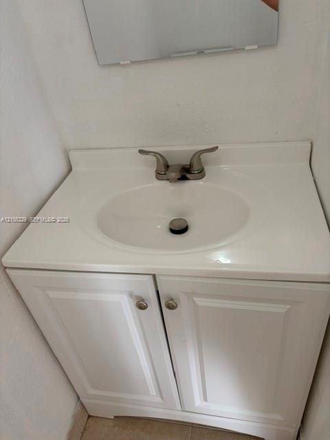 White vanity cabinet with recessed panel doors, integrated sink countertop, and dual-handle metal faucet