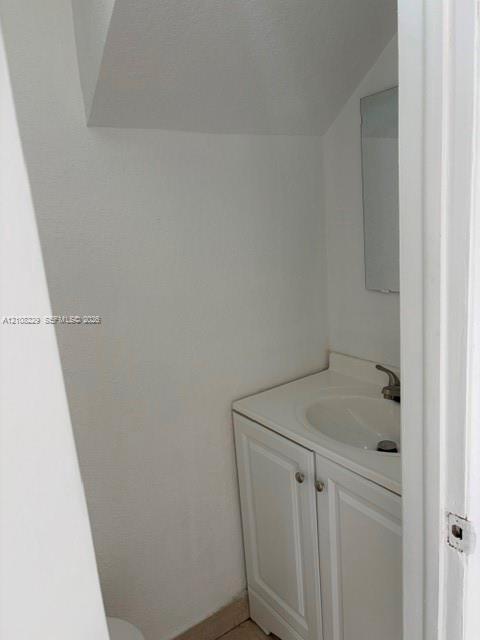 Vanity cabinet with white raised-panel doors, integrated sink countertop, single-handle faucet, and wall-mounted mirror