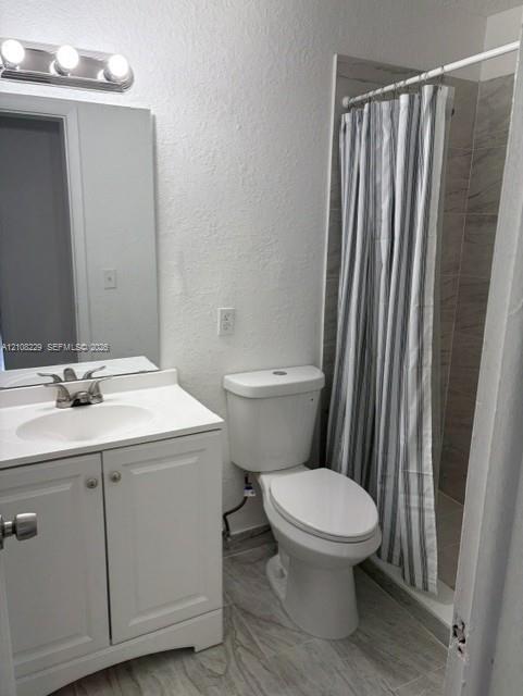 White vanity cabinet with an integrated basin, three-light wall-mounted fixture, polished chrome faucet, and neutral-toned tiled flooring