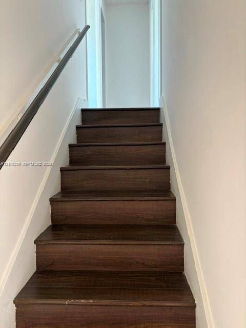 Staircase featuring wood-finish treads and a dark-toned handrail