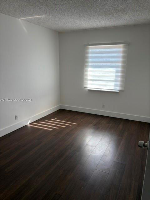 Interior room featuring wood-finish flooring, white walls, and a window with a dual-layer roller shade