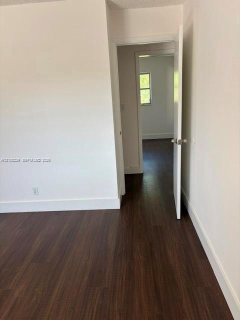 Interior room featuring white-painted walls and dark wood-finish flooring