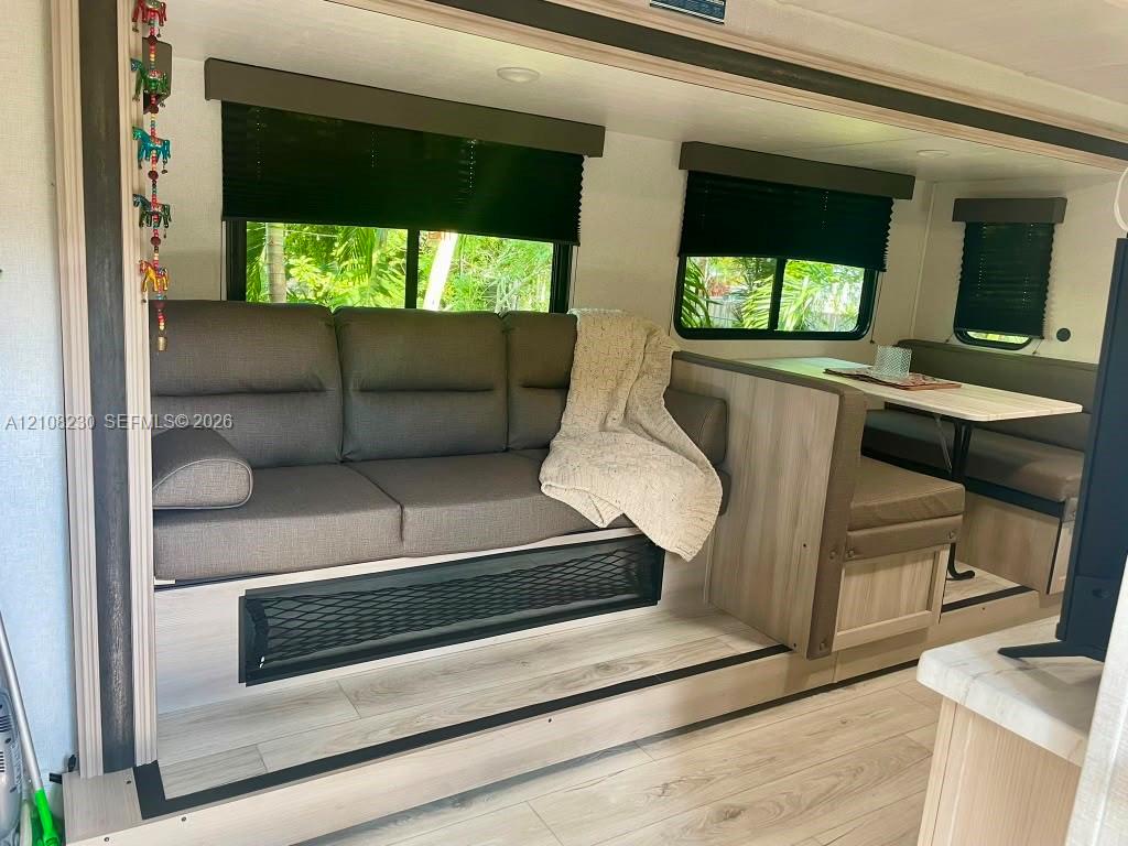 Wood-finish flooring, light-toned built-in cabinetry, neutral-toned upholstery, and multiple windows with installed blinds