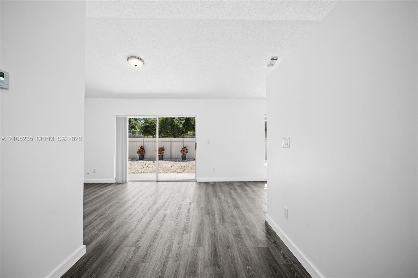Wood-finish flooring, white walls, and glass sliding door providing exterior access to a fenced rear area
