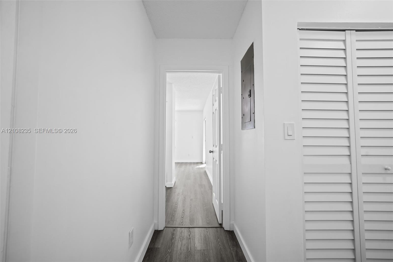 Wood-finish flooring, white walls, and bi-fold louvered closet doors