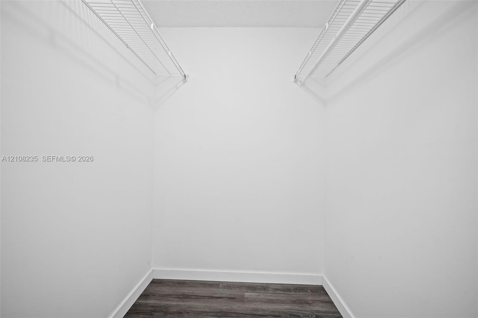 Walk-in closet featuring wood-finish flooring and dual tiers of white wire shelving