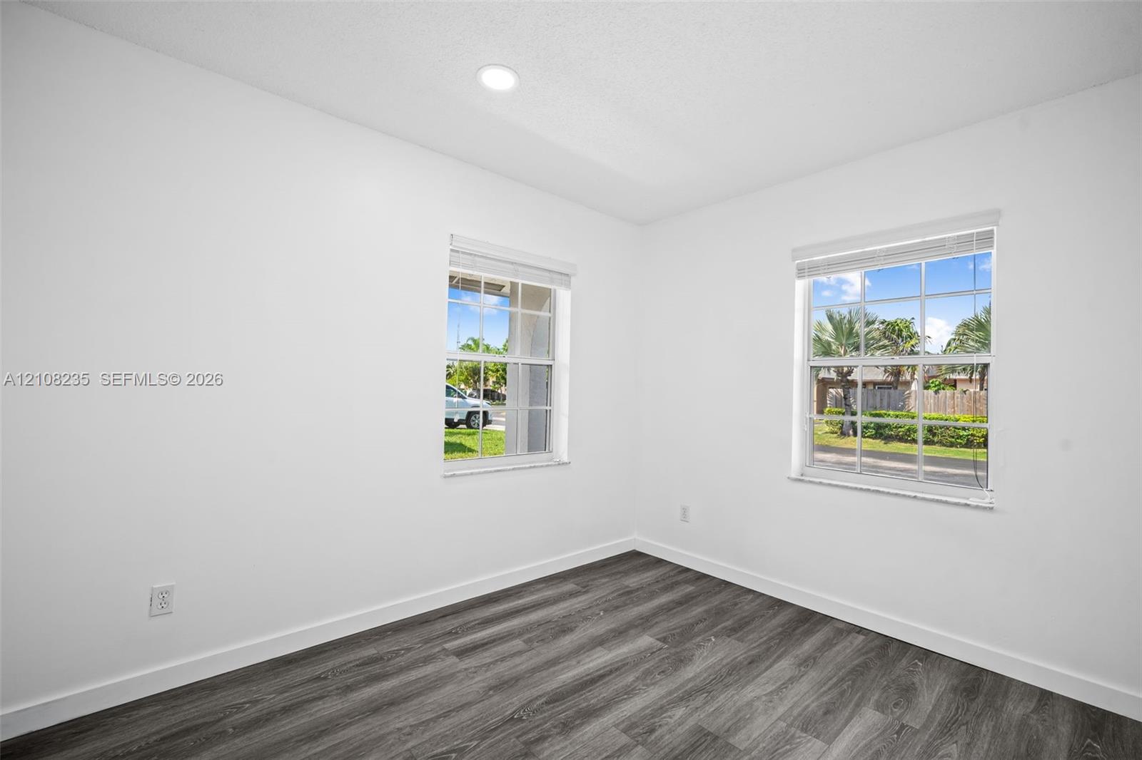 Interior room featuring neutral wall finishes, wood-finish flooring, two grid-pattern windows, and recessed lighting