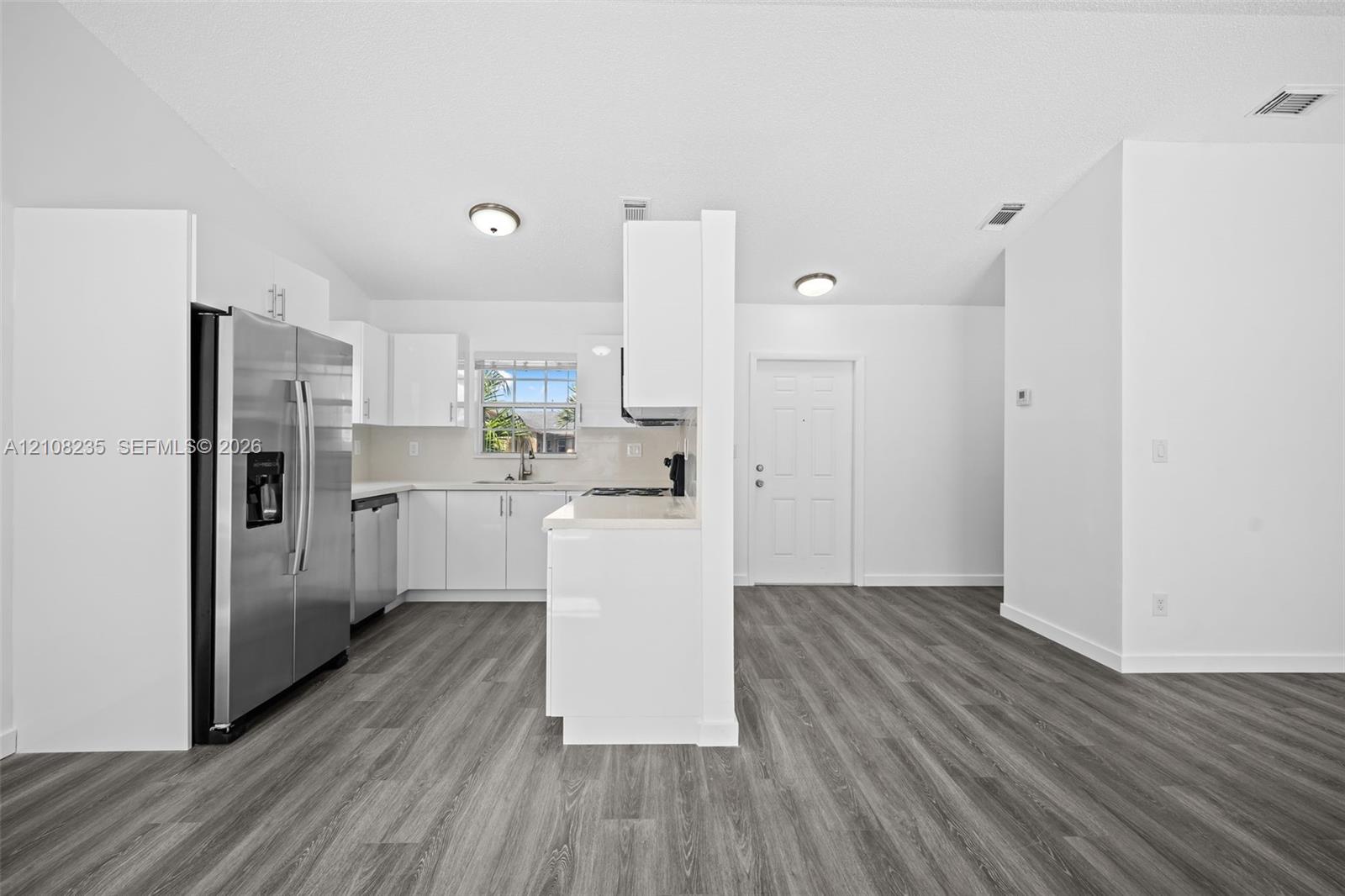 Kitchen featuring white cabinetry, wood-finish flooring, stainless steel side-by-side refrigerator, and a recessed window