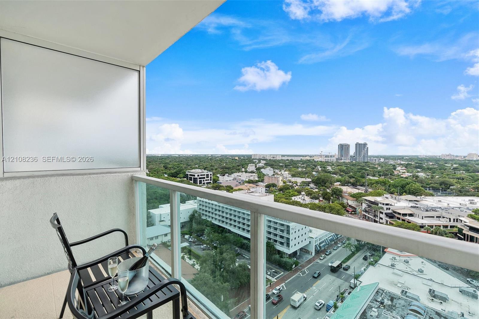 Private balcony featuring a glass-panel railing, concrete flooring, and an expansive skyline panorama