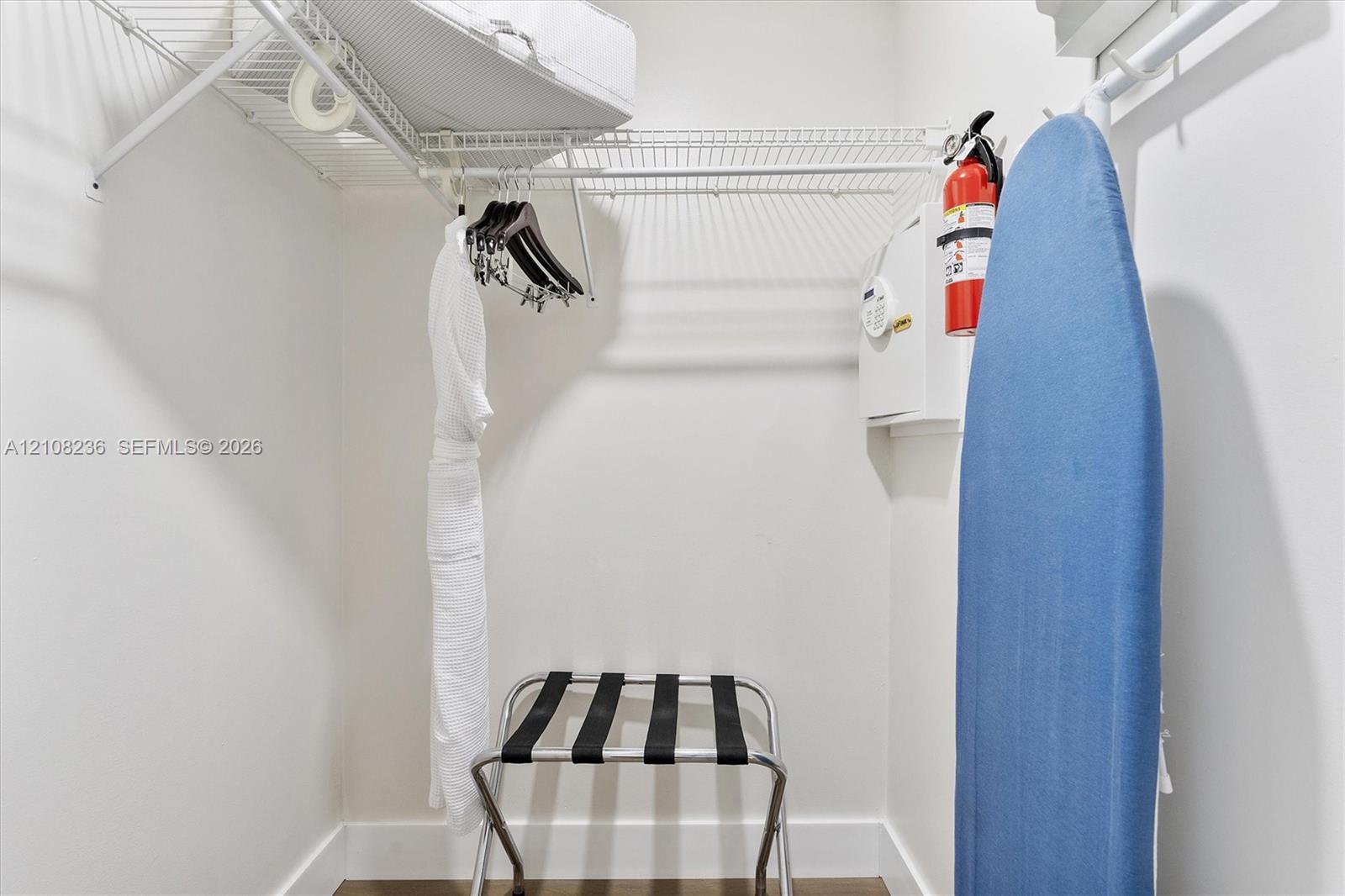 Walk-in closet featuring wire shelving, wall-mounted fire extinguisher, and built-in wall safe