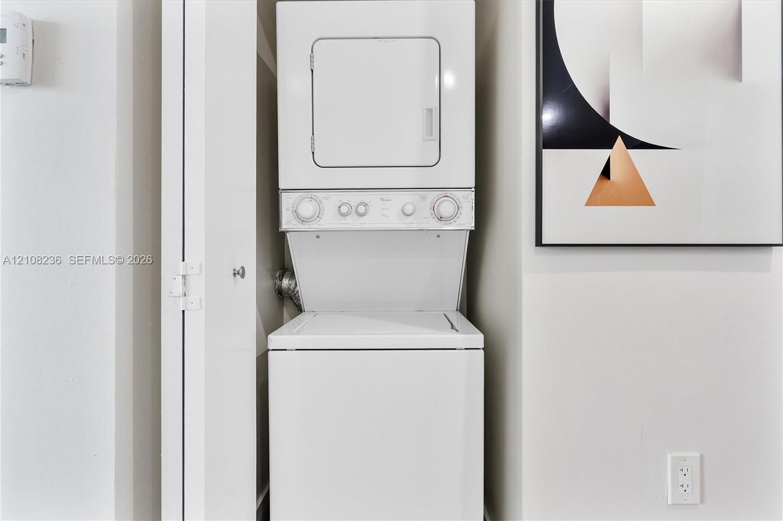 Stacked white laundry unit housed within a built-in closet