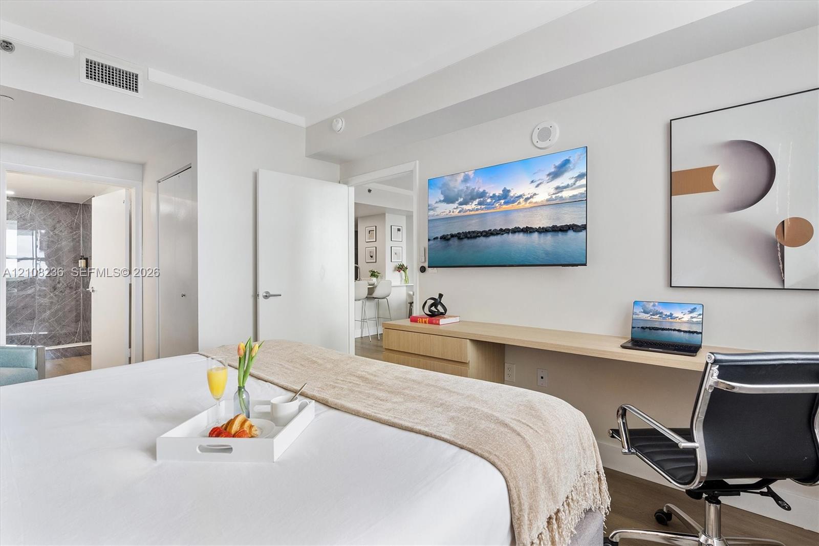 Built-in wall-mounted desk with light-finish cabinetry, wood-finish flooring, and wall-to-wall mirror paneling