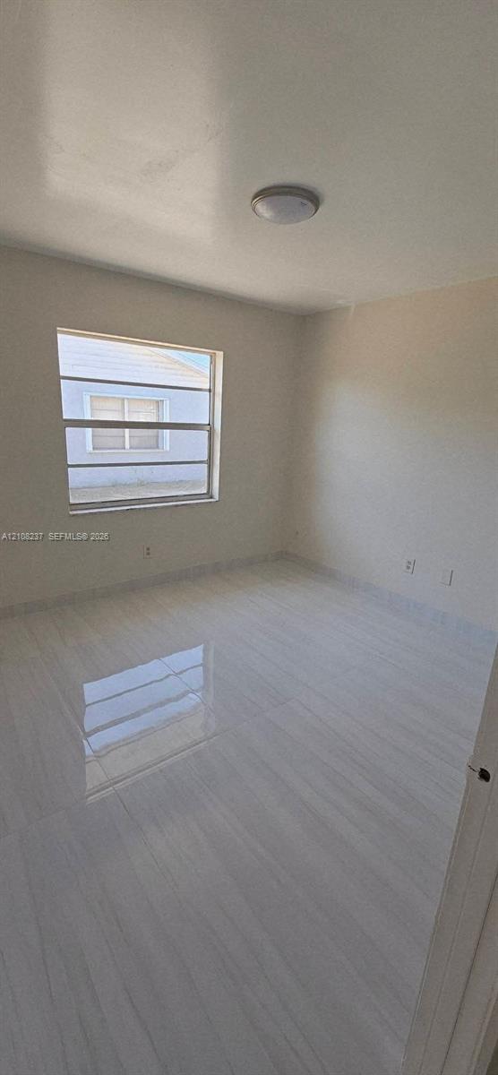Interior space featuring high-gloss tile flooring, neutral wall paint, and a multi-pane horizontal sliding window with a flush-mount overhead light fixture