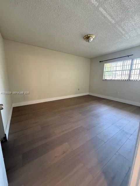 Neutral-toned interior space featuring wood-finish flooring, a window with horizontal security bars, and a flush-mount ceiling light fixture