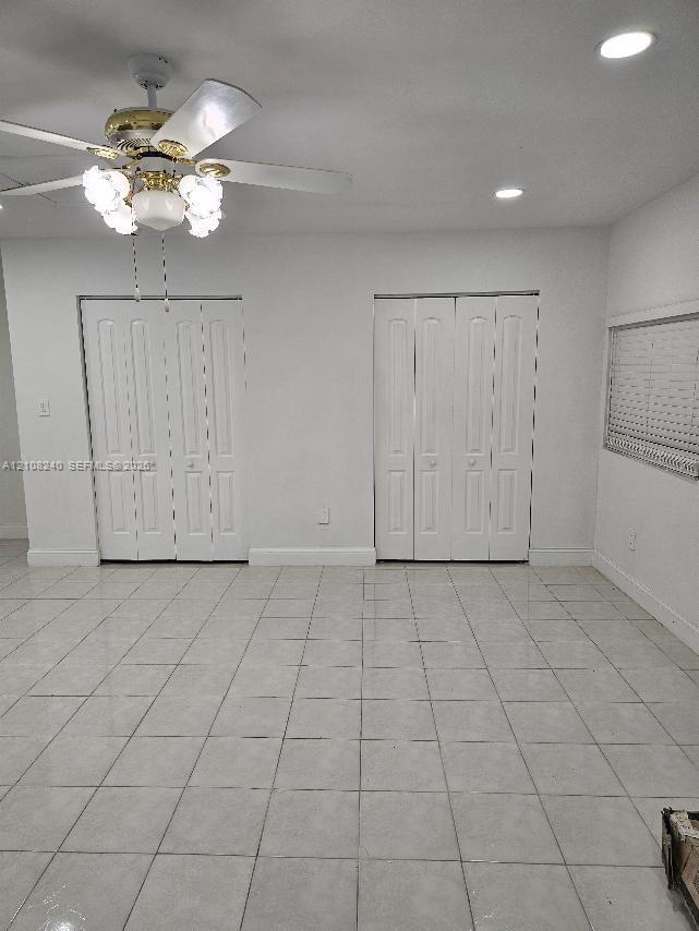 Neutral-toned tile flooring, recessed ceiling lighting, multi-light ceiling fan, and two sets of interior bi-fold closet doors