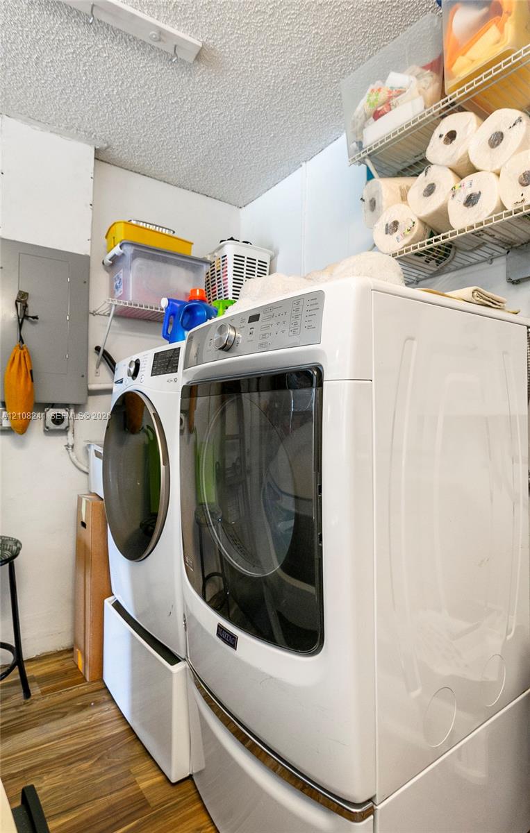 Laundry area featuring wood-finish flooring, white appliances, and built-in wire shelving