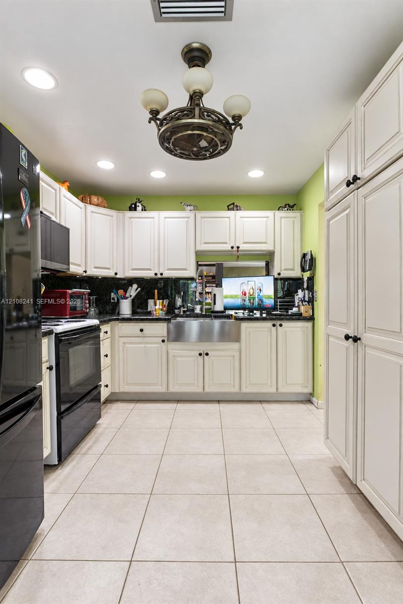 Kitchen featuring white cabinetry, stainless steel farmhouse sink, tiled flooring, recessed lighting, and a ceiling-mounted fixture Kitchen featuring white cabinetry, stainless steel farmhouse sink, tiled flooring, recessed lighting, and a ceiling-mounted fixture