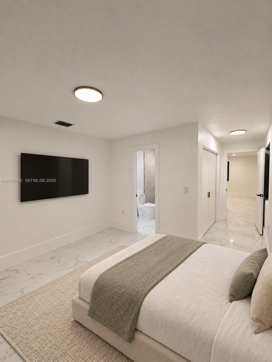 Neutral-toned interior featuring large-format stone-finish tile flooring, flush-mount circular lighting, and double-door closet storage