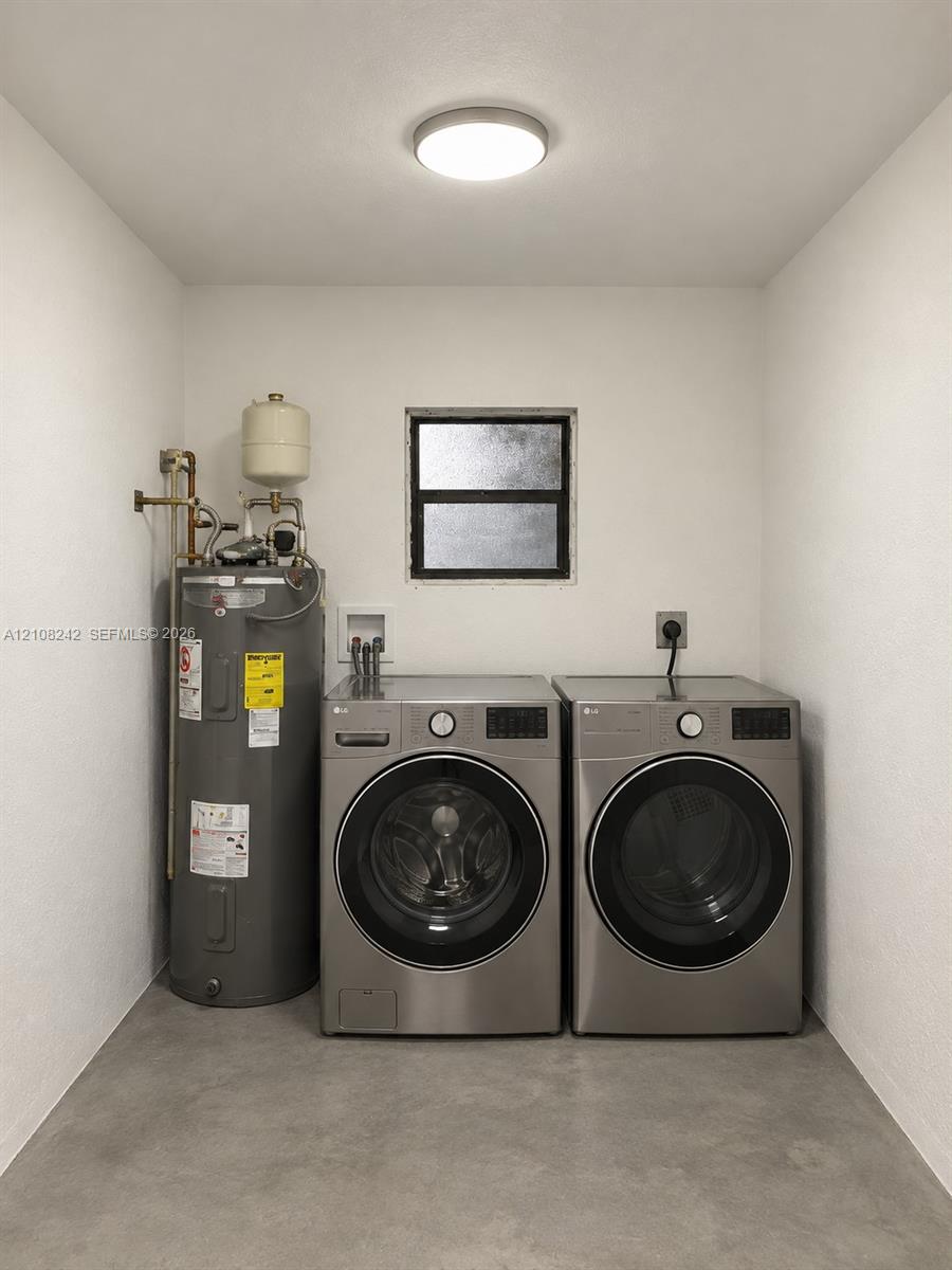 Utility space featuring a water heater, dual-stackable appliance connections, a single-hung window, and concrete flooring