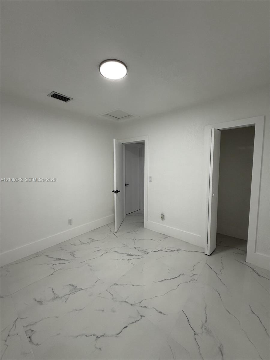 Interior space featuring polished stone-finish flooring with marbled veining and a flush-mount ceiling light fixture