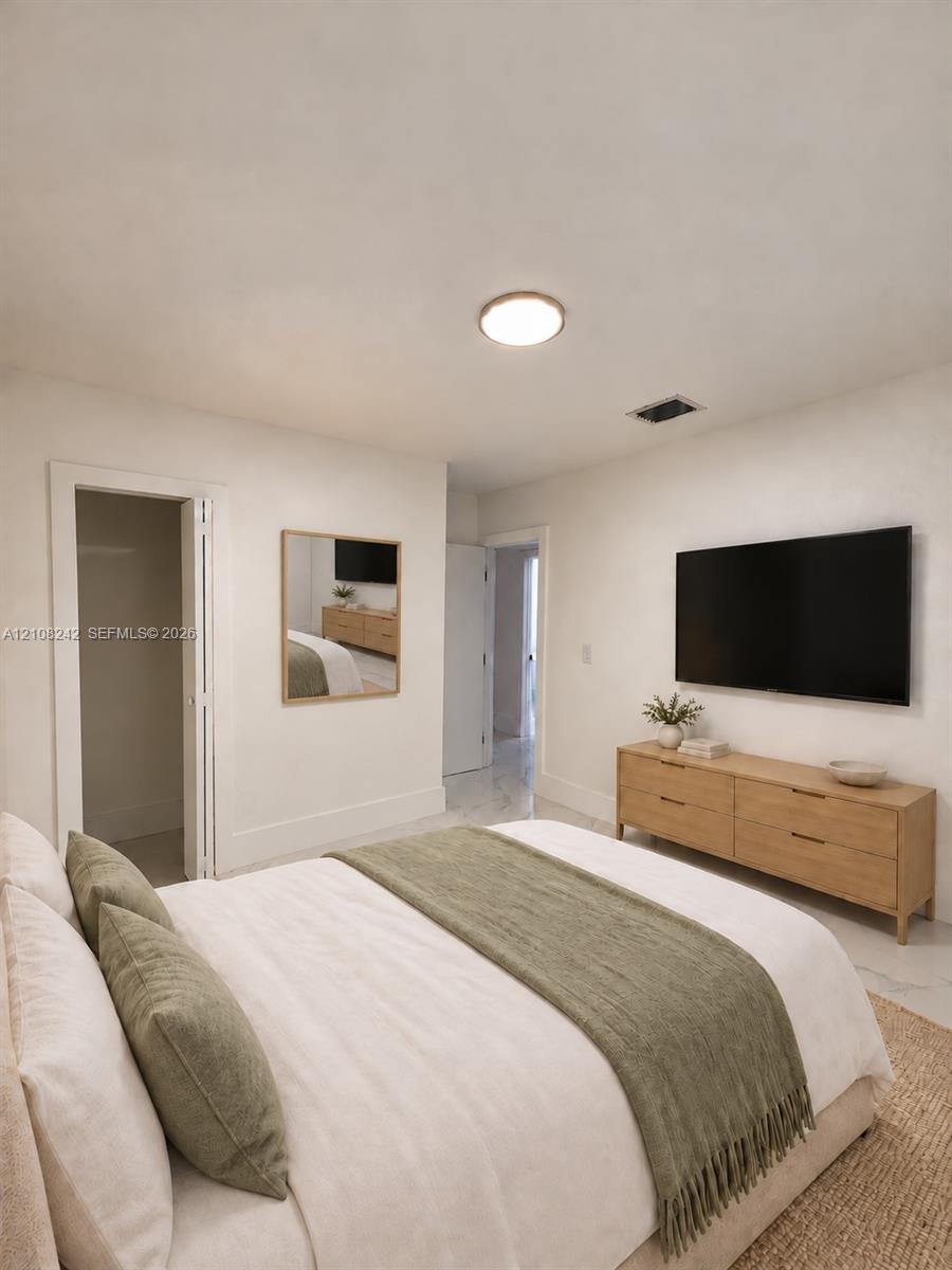 Neutral interior featuring polished stone-finish flooring, recessed lighting, and a square wall-mounted mirror with a wood-tone frame