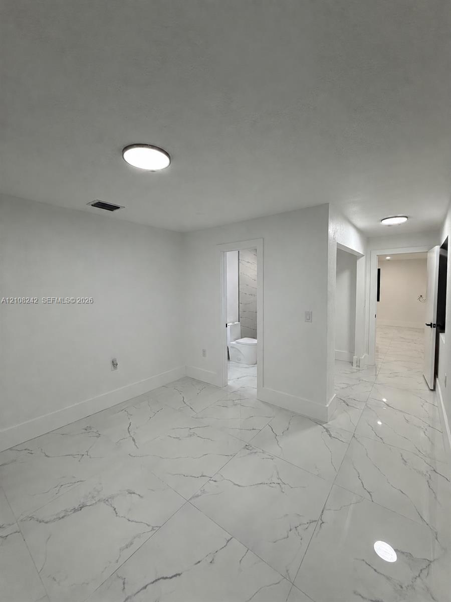 Large-format stone-finish flooring with high-gloss surfacing and flush-mount ceiling light fixtures