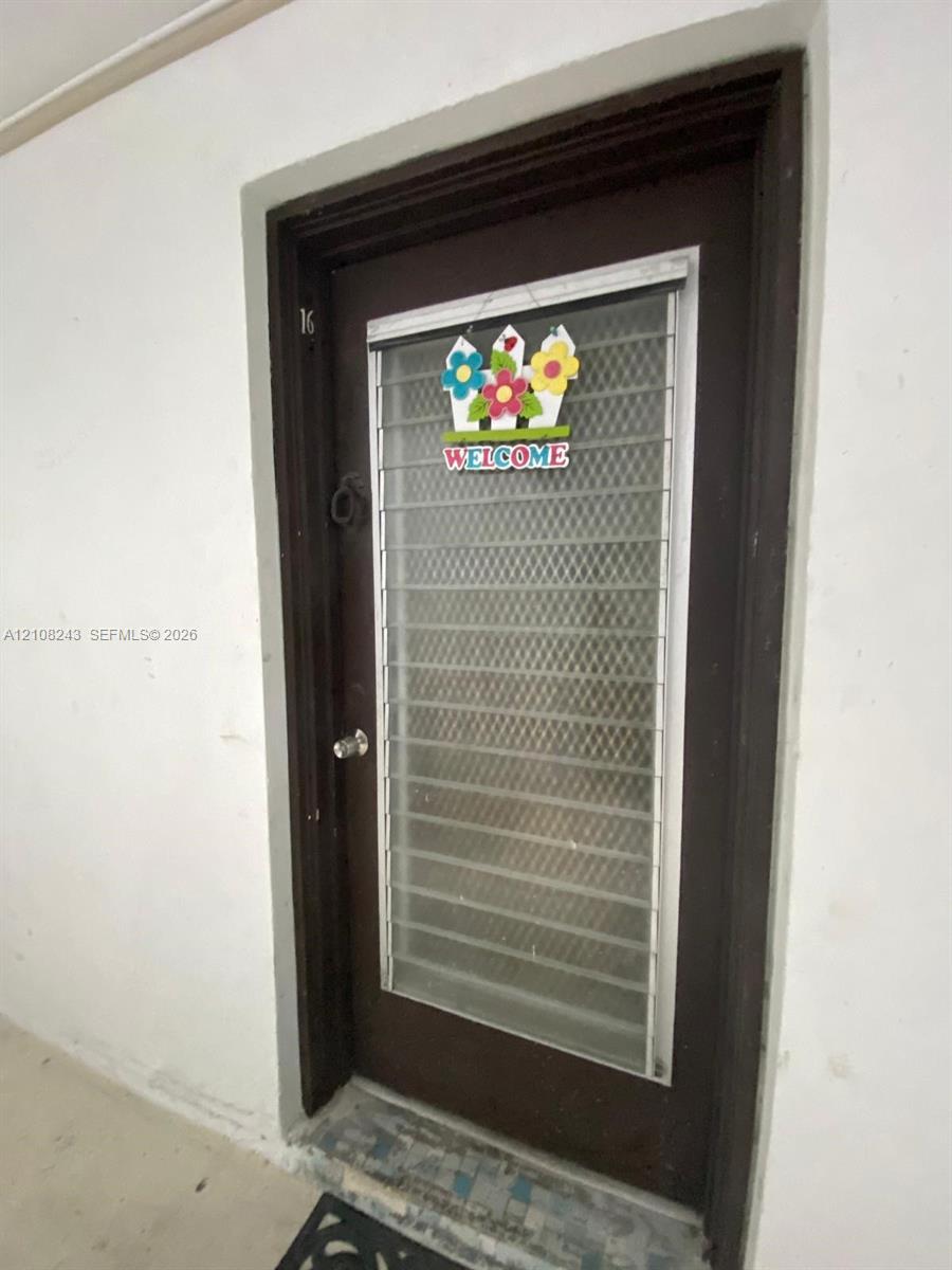 Dark-toned solid core entry door featuring a full-length metal security screen insert and integrated round-knob hardware Dark-toned solid core entry door featuring a full-length metal security screen insert and integrated round-knob hardware