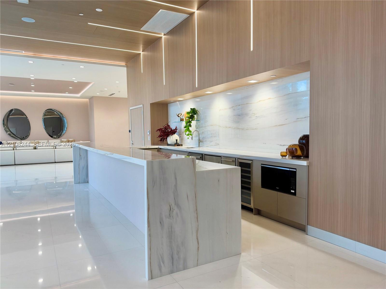 Expansive common area featuring floor-to-ceiling windows, polished stone tile flooring, recessed ceiling lighting, and layered tray ceiling detail