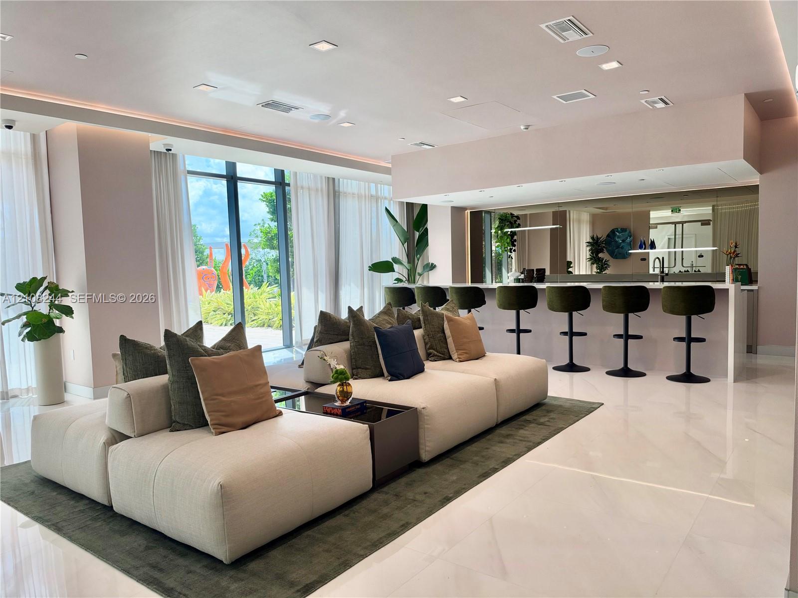 Rooftop terrace featuring a large media screen, artificial turf lawn, manicured privacy hedges, mature palm trees, and an expansive pool