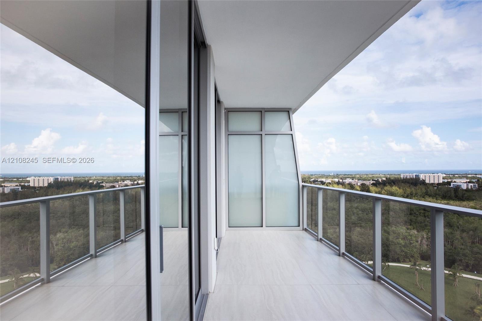 Covered balcony featuring expansive glass panel railings, floor-to-ceiling sliding glass doors, and tiled flooring