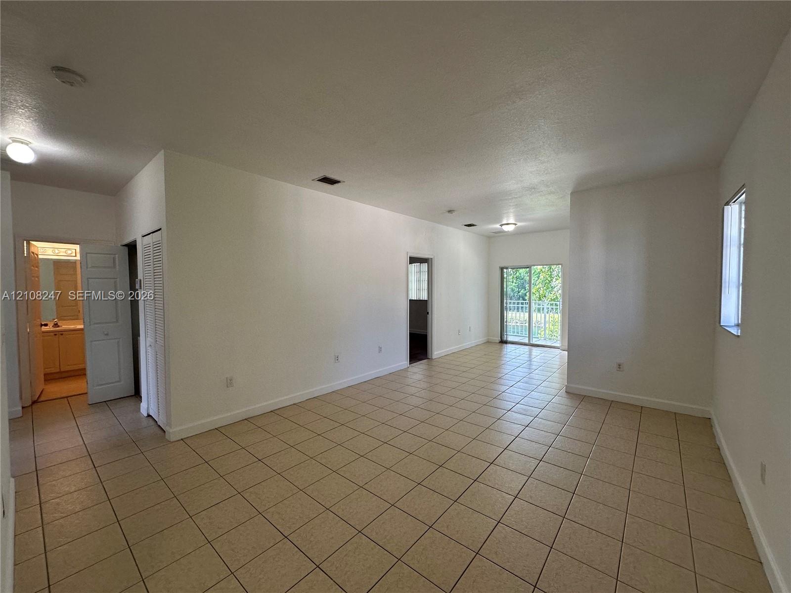Open-concept interior featuring neutral tile flooring, sliding glass doors, and flush-mount ceiling lighting