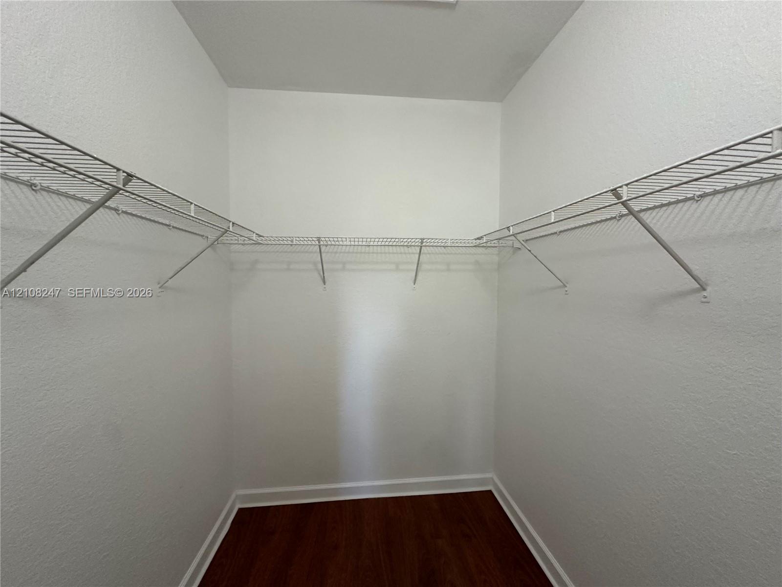 Storage space featuring white wire shelving and wood-finish flooring