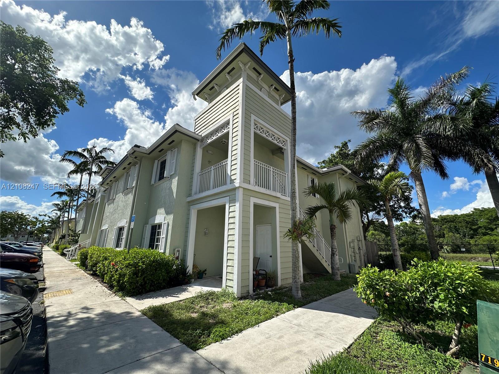 Two-story building featuring horizontal lap siding, a decorative cupola, private balconies with white railings, and an exterior staircase