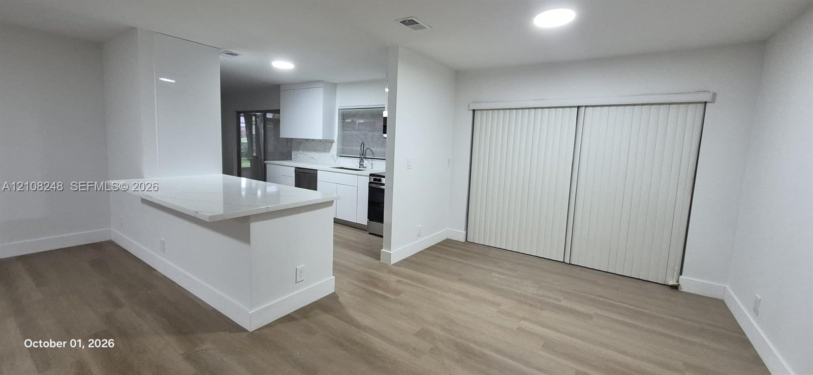 Kitchen featuring white cabinetry, stone-finish countertops, stainless steel appliances, wood-finish flooring, and sliding glass doors