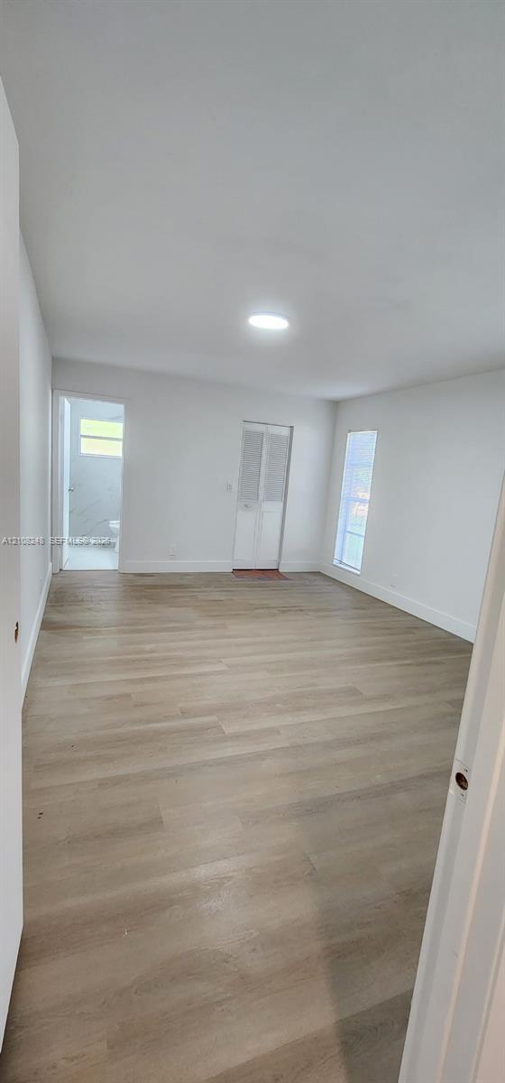 Room featuring wood-finish flooring, recessed lighting, and vertical windows