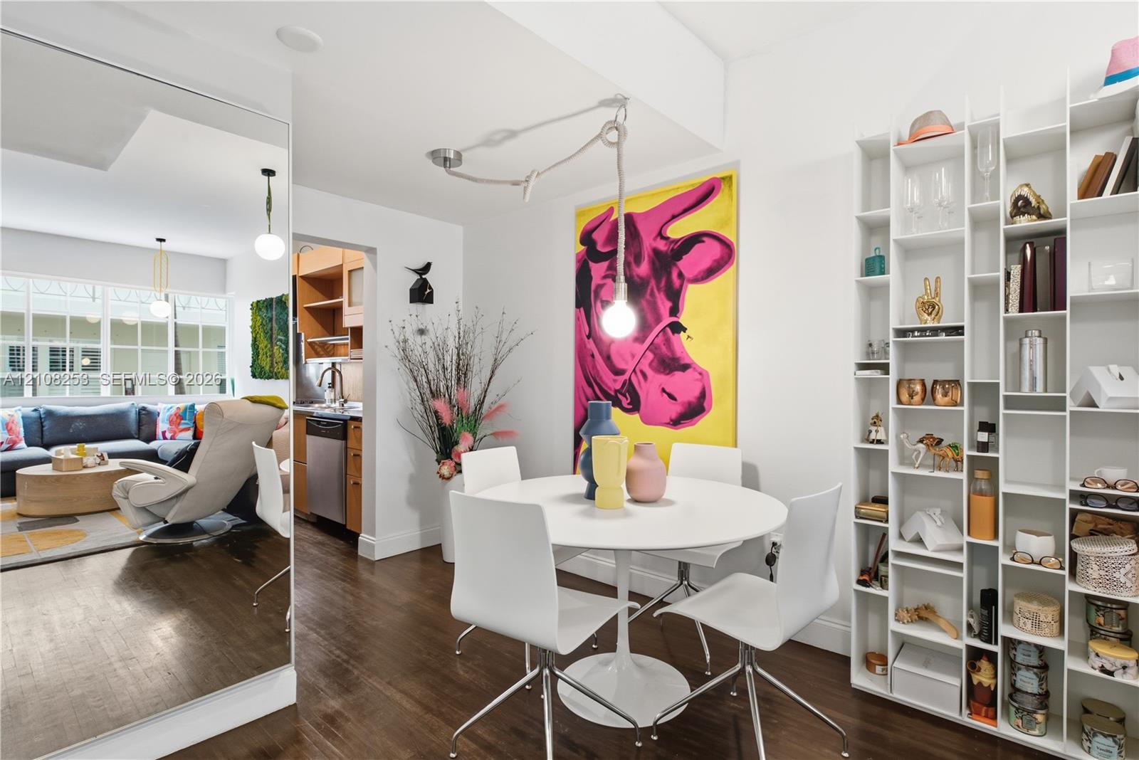 Floor-to-ceiling wall mirror, built-in floor-to-ceiling white shelving unit, and dark wood-finish flooring