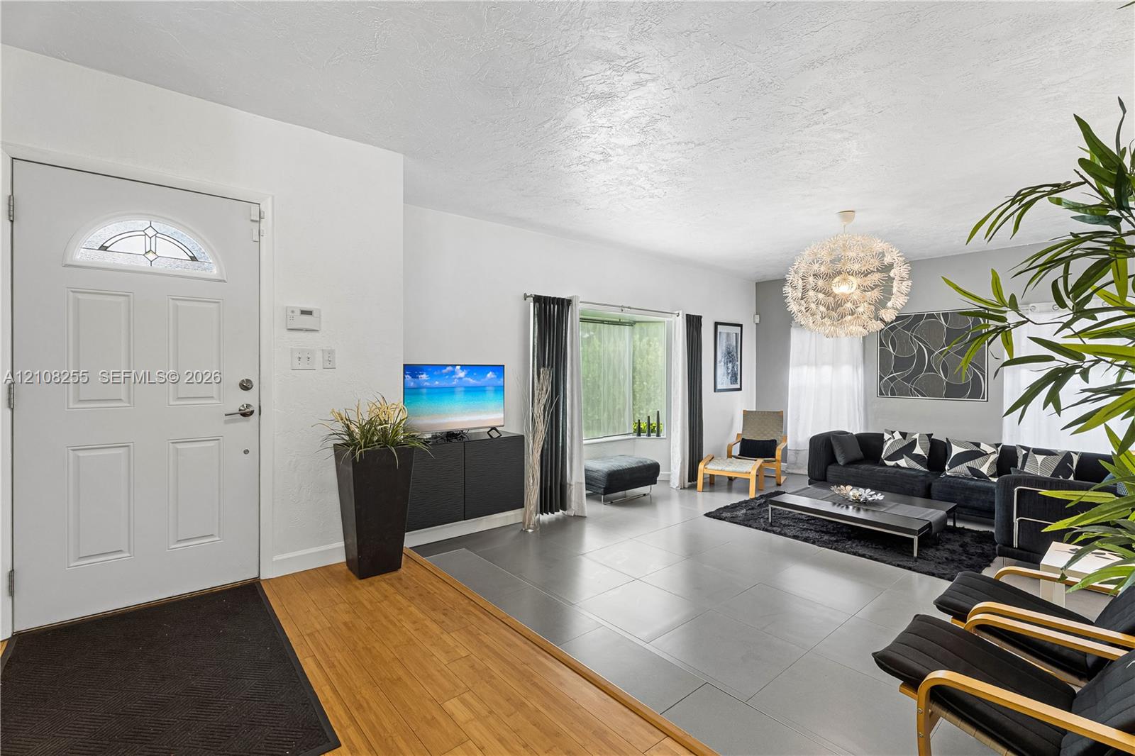 Entrance featuring a semi-circular transom window, large-format tile flooring, wood-finish entryway flooring, and a spherical tiered chandelier