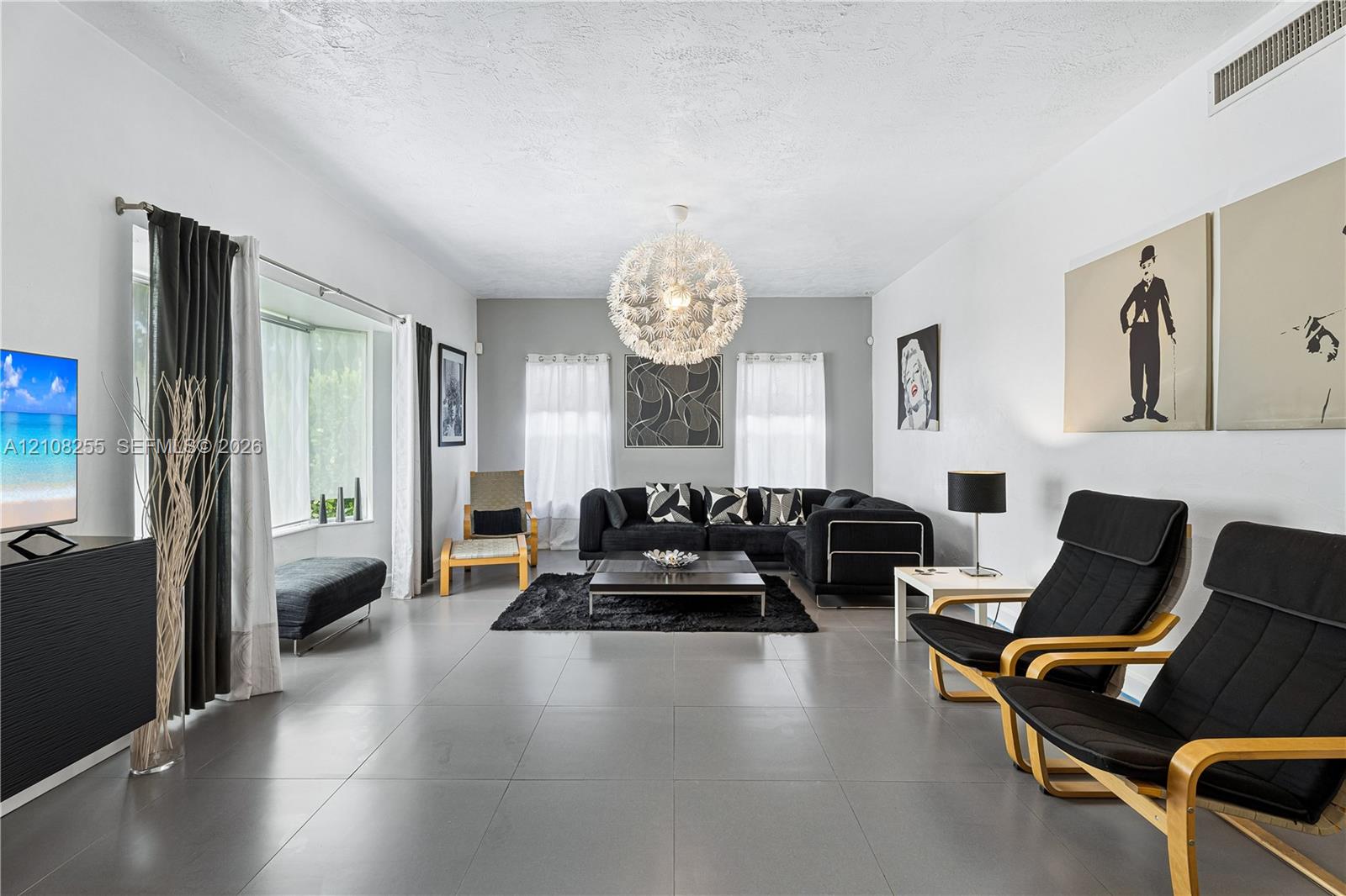 Large-format tile flooring, oversized bay window, and contemporary spherical chandelier