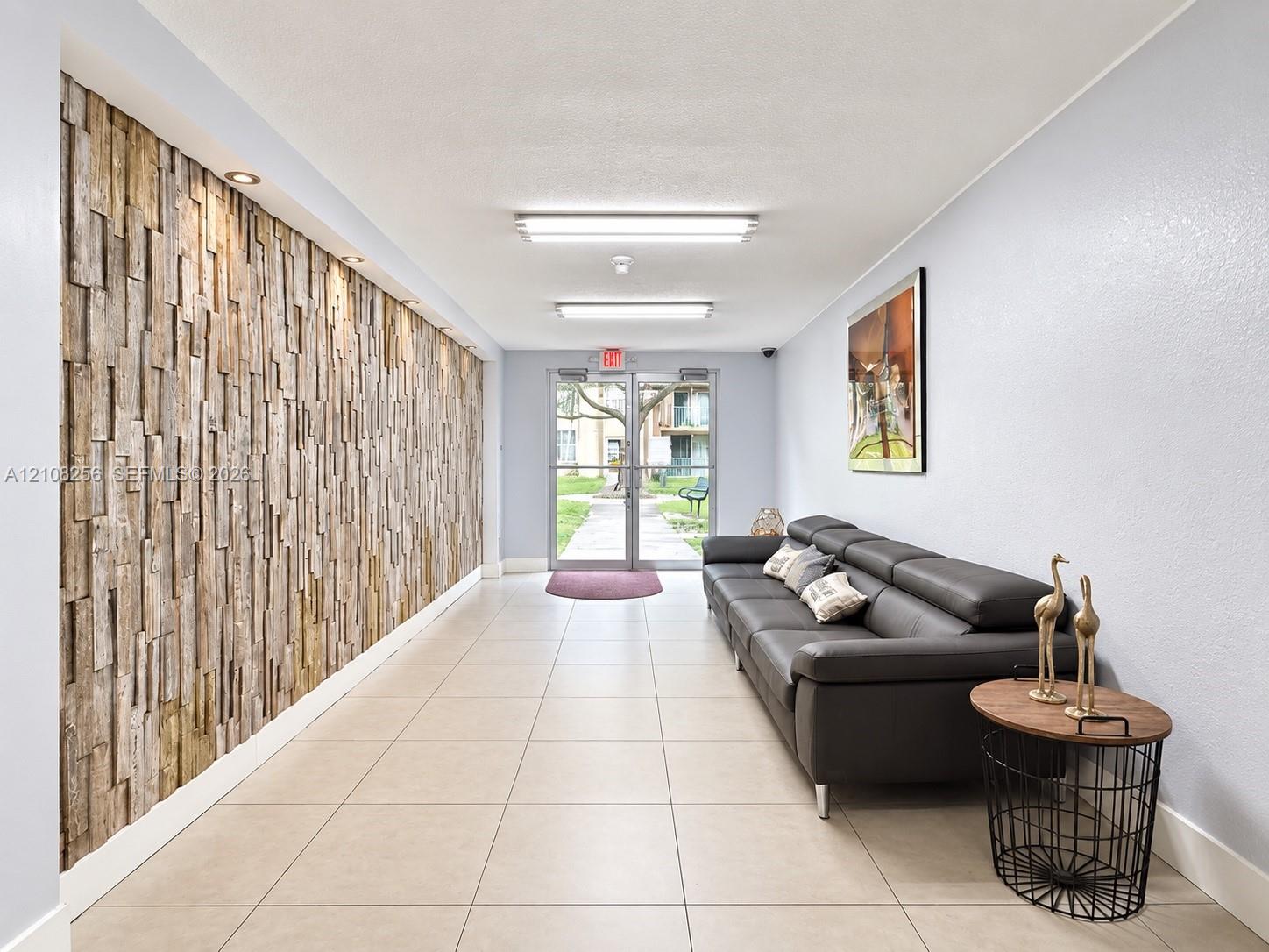 Entrance lobby featuring a textured wood-plank accent wall, large-format tile flooring, and recessed ceiling lighting