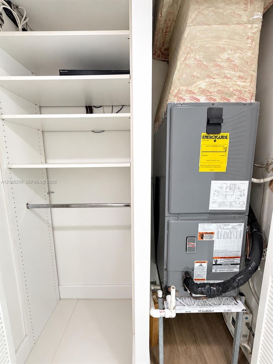 Built-in white shelving with a metal hanging rod and a utility closet containing a mechanical HVAC system
