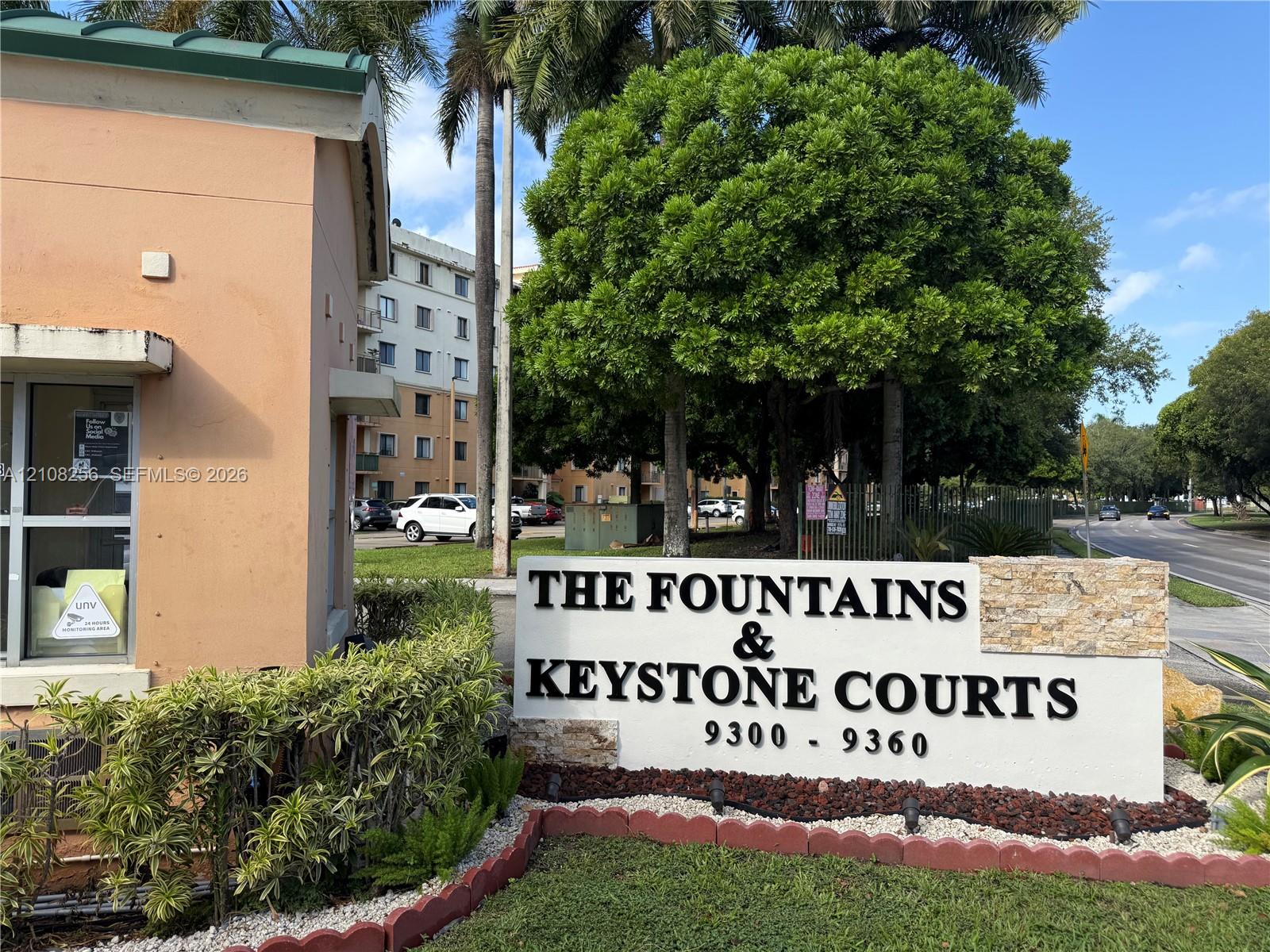 Monument-style stone and stucco signage featuring dimensional lettering, surrounded by manicured landscaping and mature trees