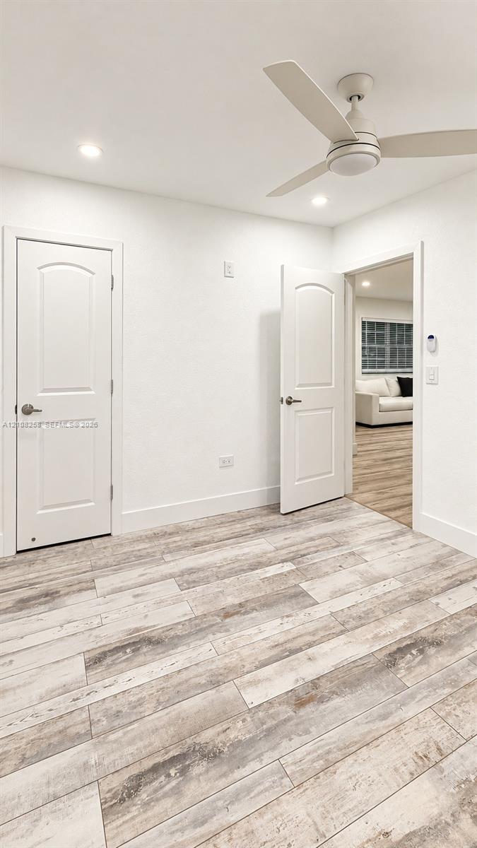 Wood-finish flooring, three-blade ceiling fan with integrated light, and two-panel interior doors with brushed nickel hardware