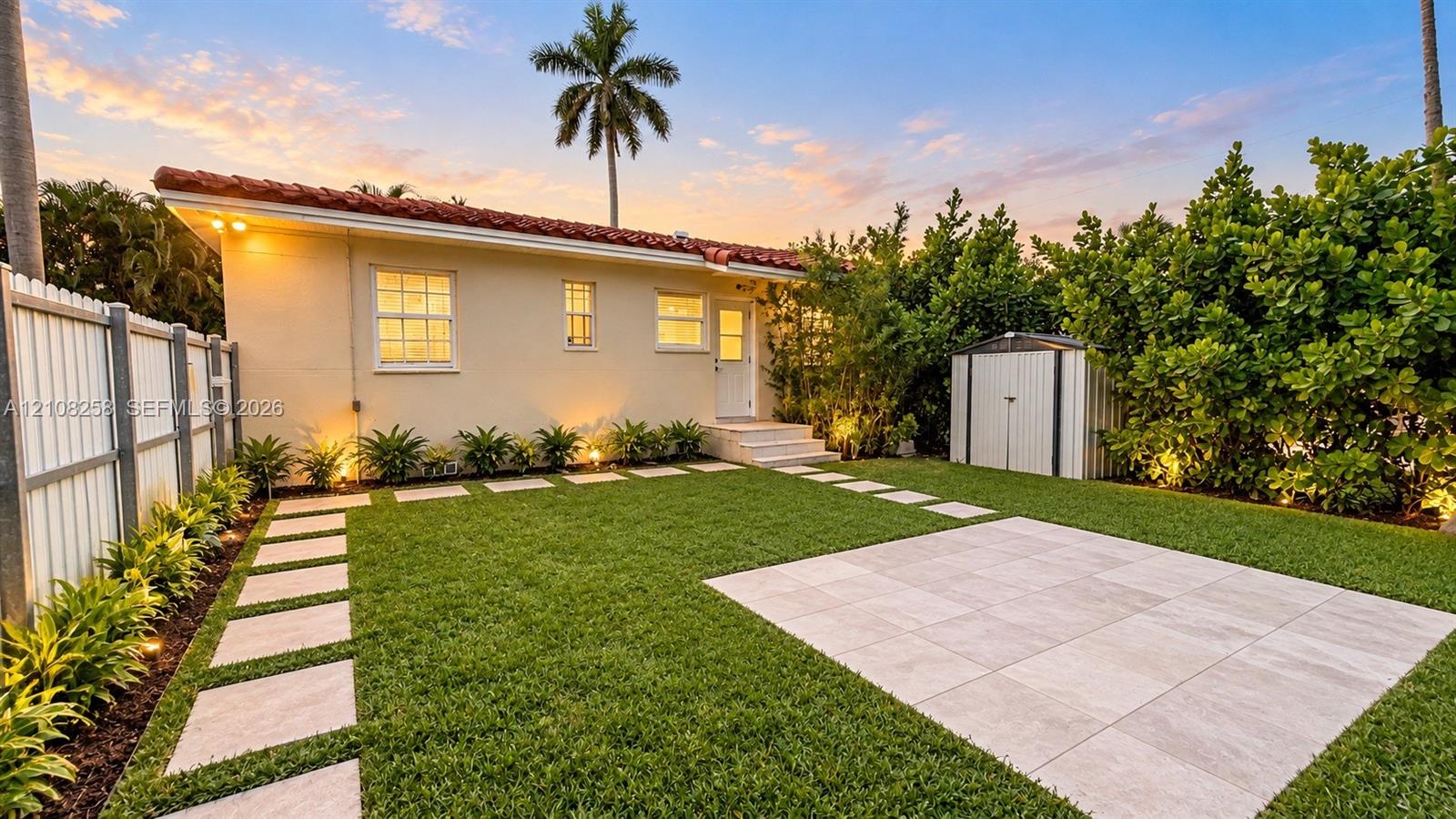 Rear exterior featuring a tile roof, paved patio area, grid-patterned stone walkway, and privacy fencing