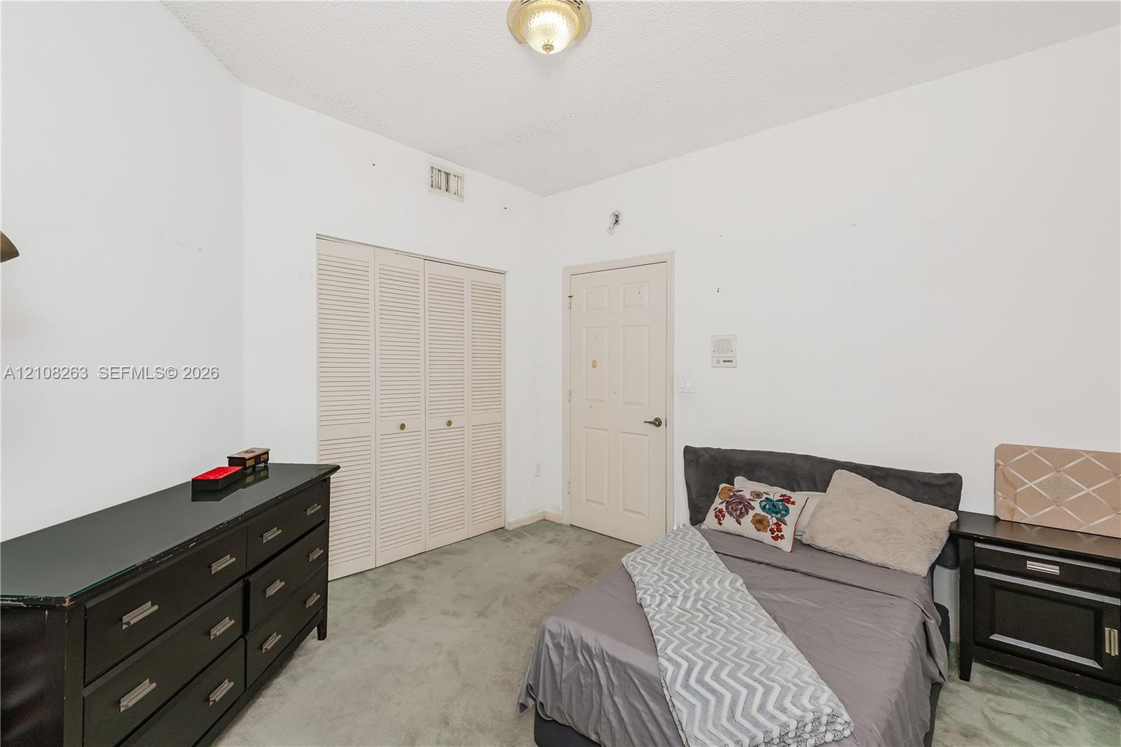 Room featuring carpeting, bifold closet doors, a paneled interior door, and a flush-mount ceiling light fixture