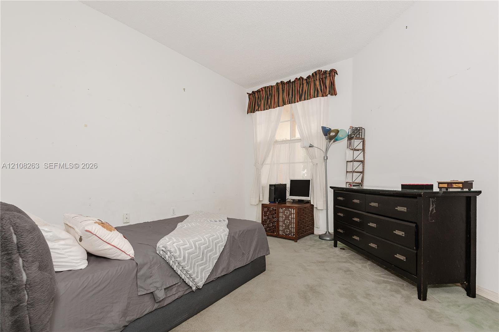 Interior room featuring neutral wall finishes, wall-to-wall carpeting, and a window with a fabric valance