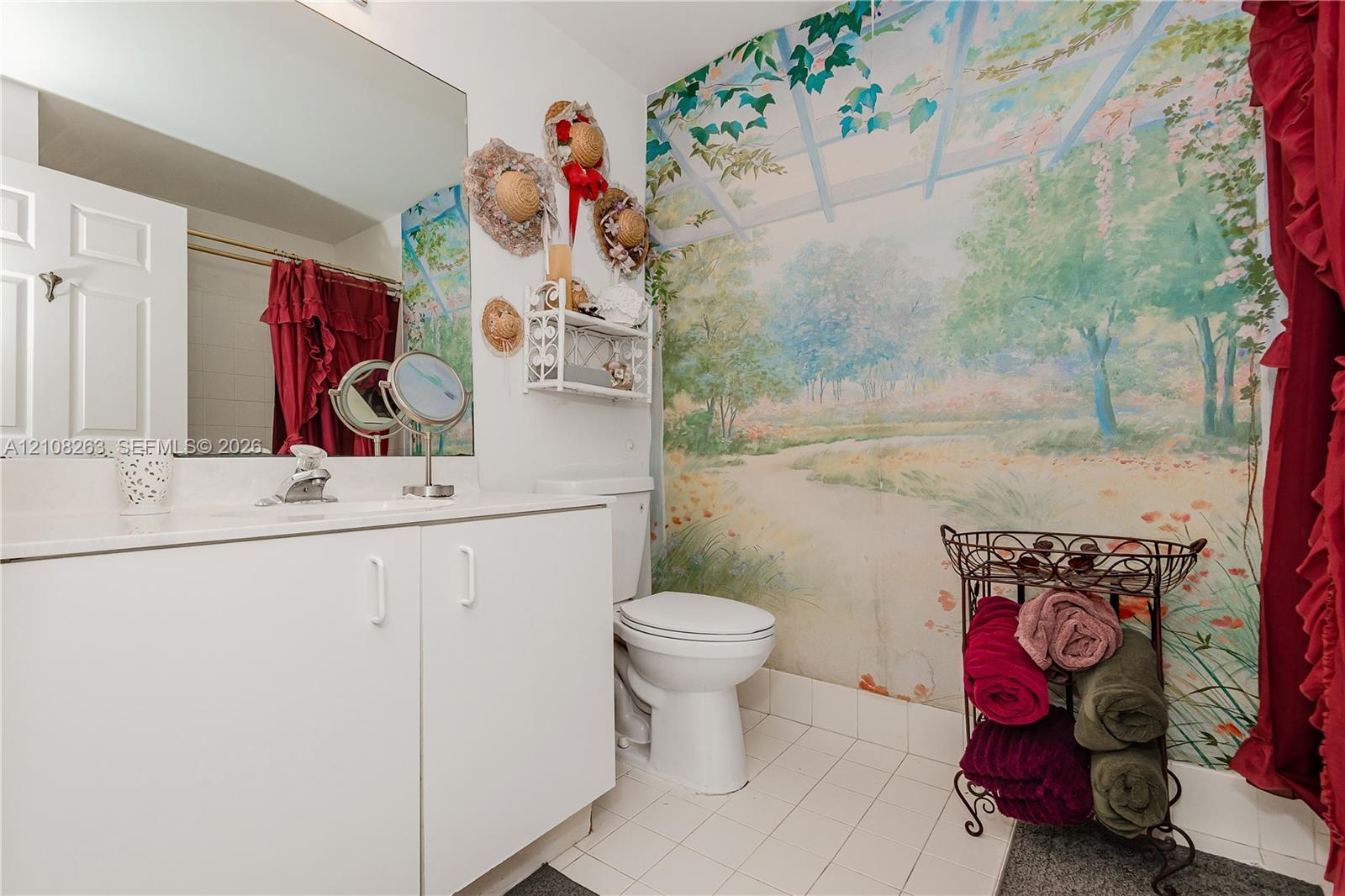 Bathroom featuring a white vanity cabinet, a large wall-mounted mirror, a porcelain toilet, and tile flooring